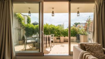 Una habitación con puerta corrediza de vidrio que da a un patio exterior, un sofá con cojines estampados y piso de madera.