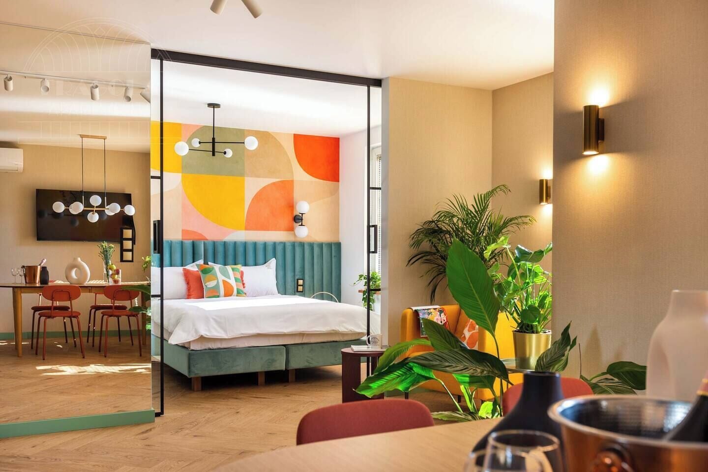 A modern hotel room with a bed, a dining area, and a living space.