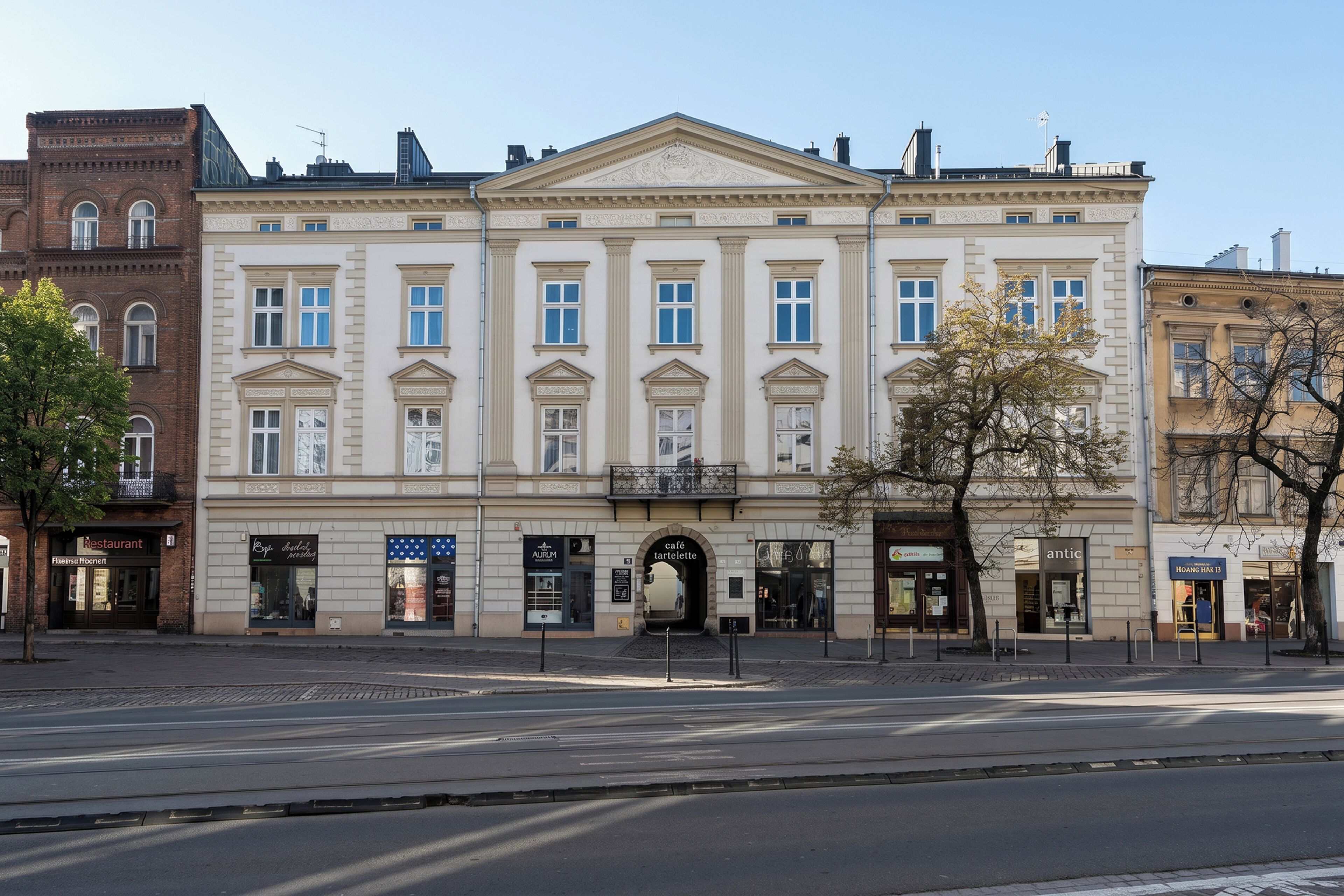A classical building with a central entrance, multiple windows, and storefronts on the ground floor.