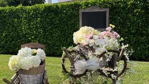 A garden setting with a wooden bench, wicker baskets, and a decorative arrangement of flowers and greenery. - Hotel Poppi (Mira)