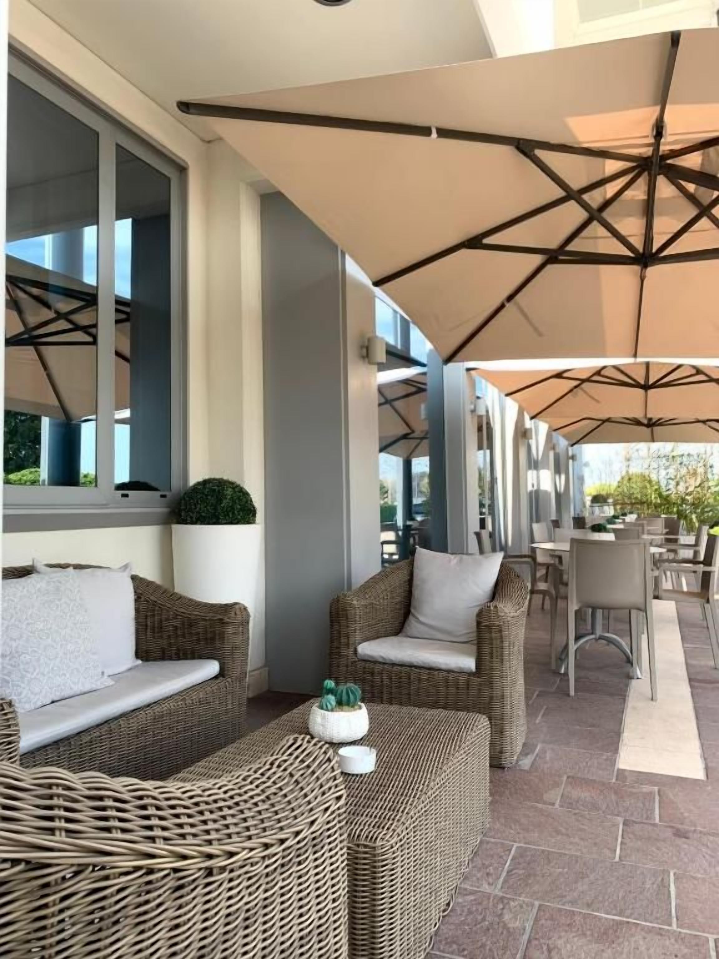 An outdoor seating area with wicker furniture and umbrellas.