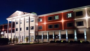 A hotel with a central entrance, a restaurant, and multiple floors with illuminated windows. - Hotel Poppi (Mira)