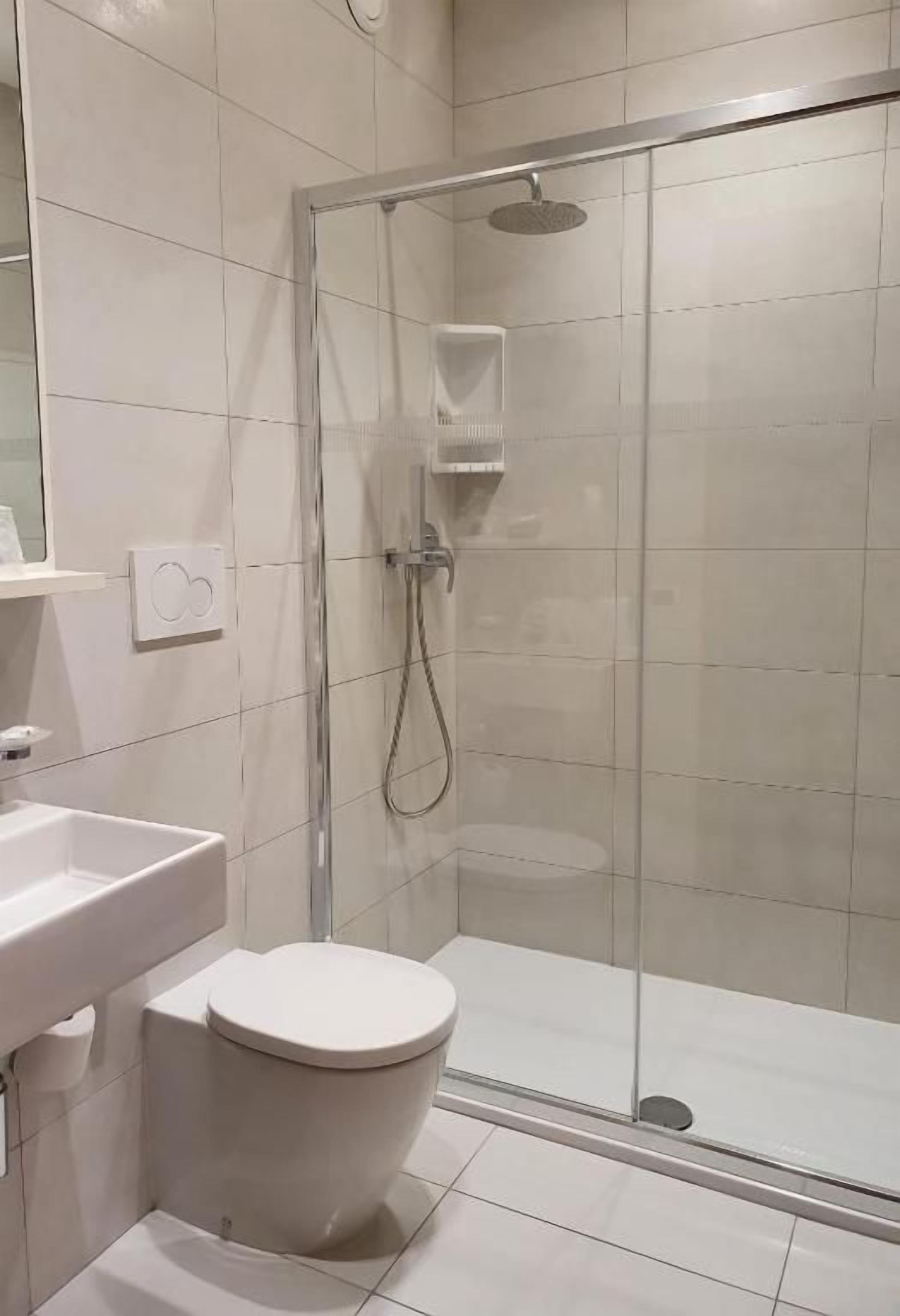 A modern bathroom with a glass-enclosed shower, a white toilet, and a sink.