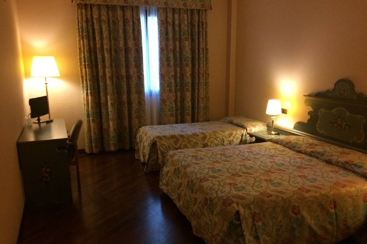 Ein Hotelzimmer mit zwei Betten, einem Schreibtisch und Lampen.
