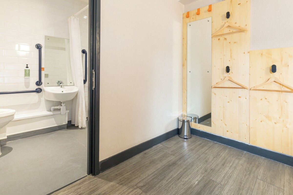 Une salle de bain avec un lavabo, des toilettes et une baignoire. Il y a un miroir et des casiers en bois accrochés au mur.