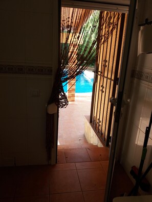 A doorway leading to a tiled patio area with a pool.