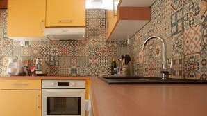 A kitchen with yellow cabinets, a white oven, and a patterned backsplash.