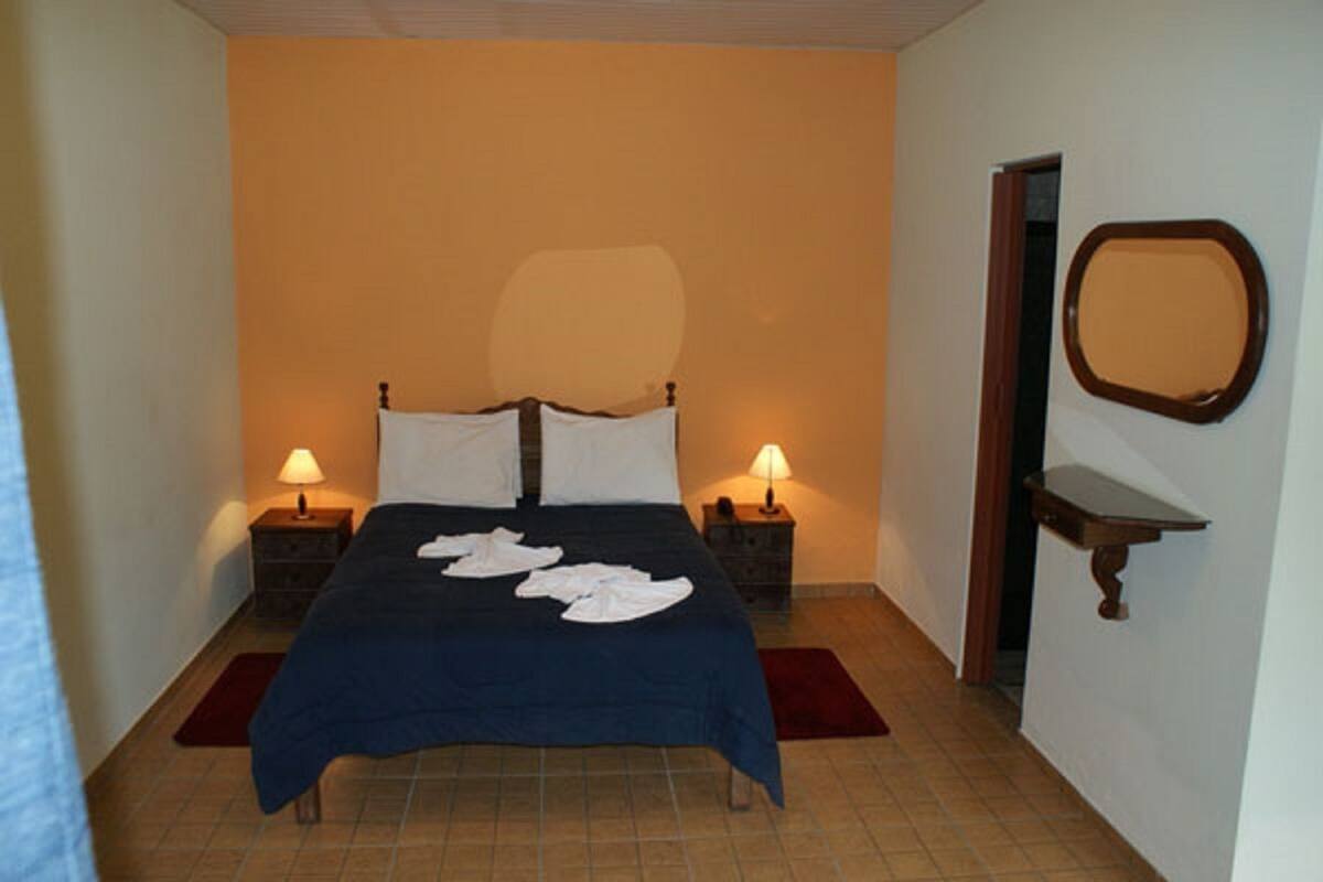 A bedroom with a bed, two bedside tables, a nightstand, a mirror, and a red rug.