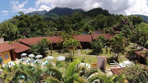 A resort with multiple buildings, a pool area with umbrellas, and lush greenery. - Hotel Fazendinha (Itatiaia)