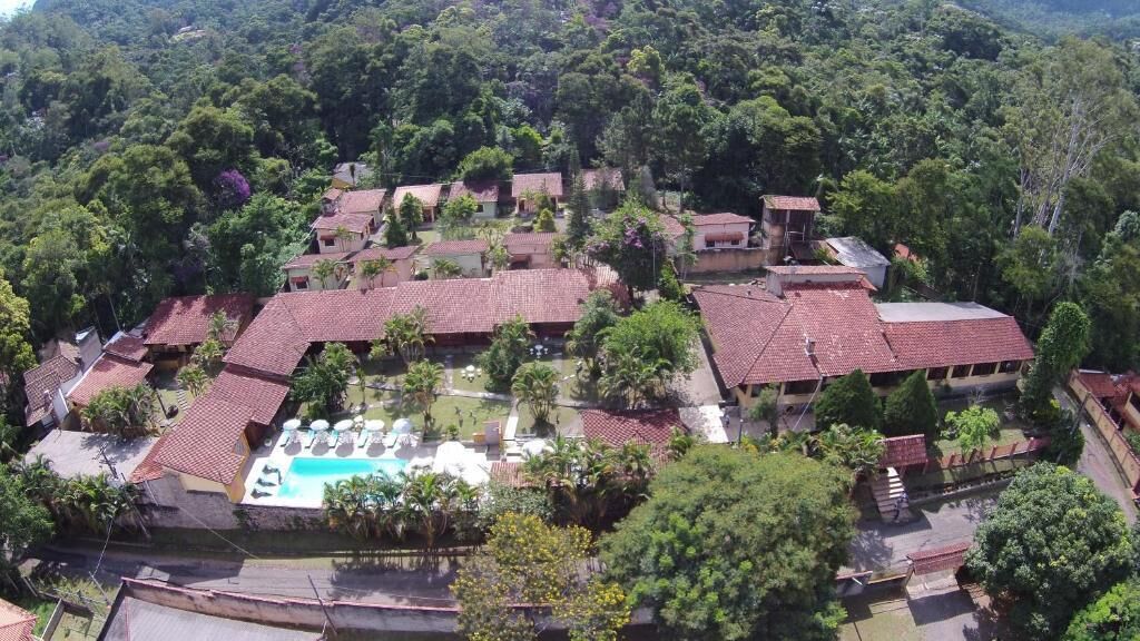 Vista aérea de um resort com vários edifícios, piscina e vegetação exuberante.