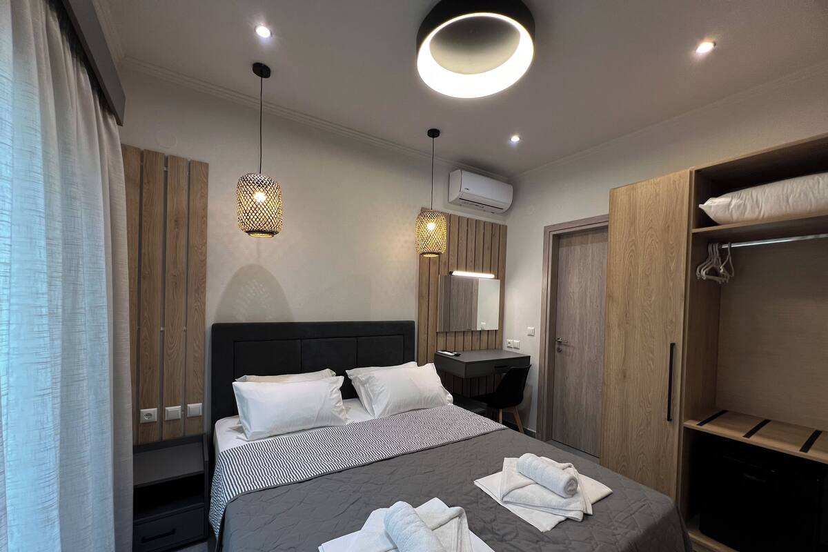 A modern bedroom with a bed, bedside table, wardrobe, and a mirror.
