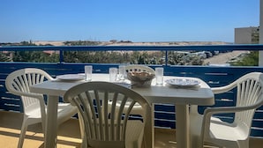 A balcony with a table and chairs, overlooking a coastal landscape. - Appartement Bleu Azur by Agence Bru - 2051 (Lacanau)