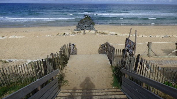 A beach pathway leading to the ocean with wooden railings and a rocky outcrop in the distance. - Appartement Bleu Azur by Agence Bru - 2051 (Lacanau)