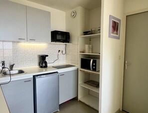 A compact kitchen with a microwave, coffee maker, and a dishwasher.