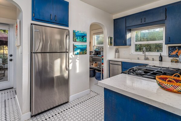 Una cocina moderna con electrodomésticos de acero inoxidable, armarios azules y suelo de baldosas.