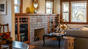 Ein gemütliches Wohnzimmer mit Kamin, Holzmöbeln und großen Fenstern.