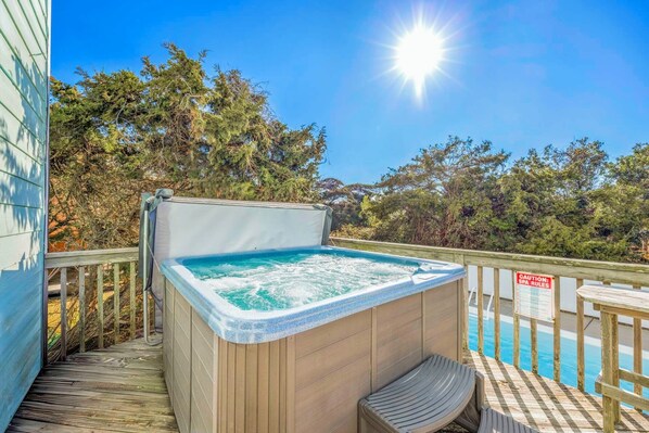 A hot tub on a wooden deck with a pool in the background, surrounded by trees. - Oceanview Home with Private Pool, Hot Tub, Game Room, and Screened Porch (Salvo)
