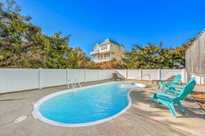 A backyard with a swimming pool, a wooden deck, and a house in the background. - Oceanview Home with Private Pool, Hot Tub, Game Room, and Screened Porch (Salvo)