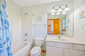 A bathroom with a bathtub, toilet, and vanity with a sink and mirror. - Oceanview Home with Private Pool, Hot Tub, Game Room, and Screened Porch (Salvo)