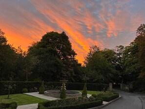 A formal garden with a central fountain, neatly trimmed hedges, and a variety of trees. - Manor House Lindley (Huddersfield)