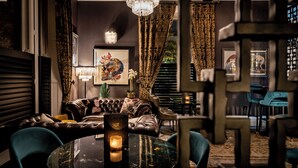 A luxurious living room with a leather sofa, a round glass table with a candle, and a chandelier. - Manor House Lindley (Huddersfield)