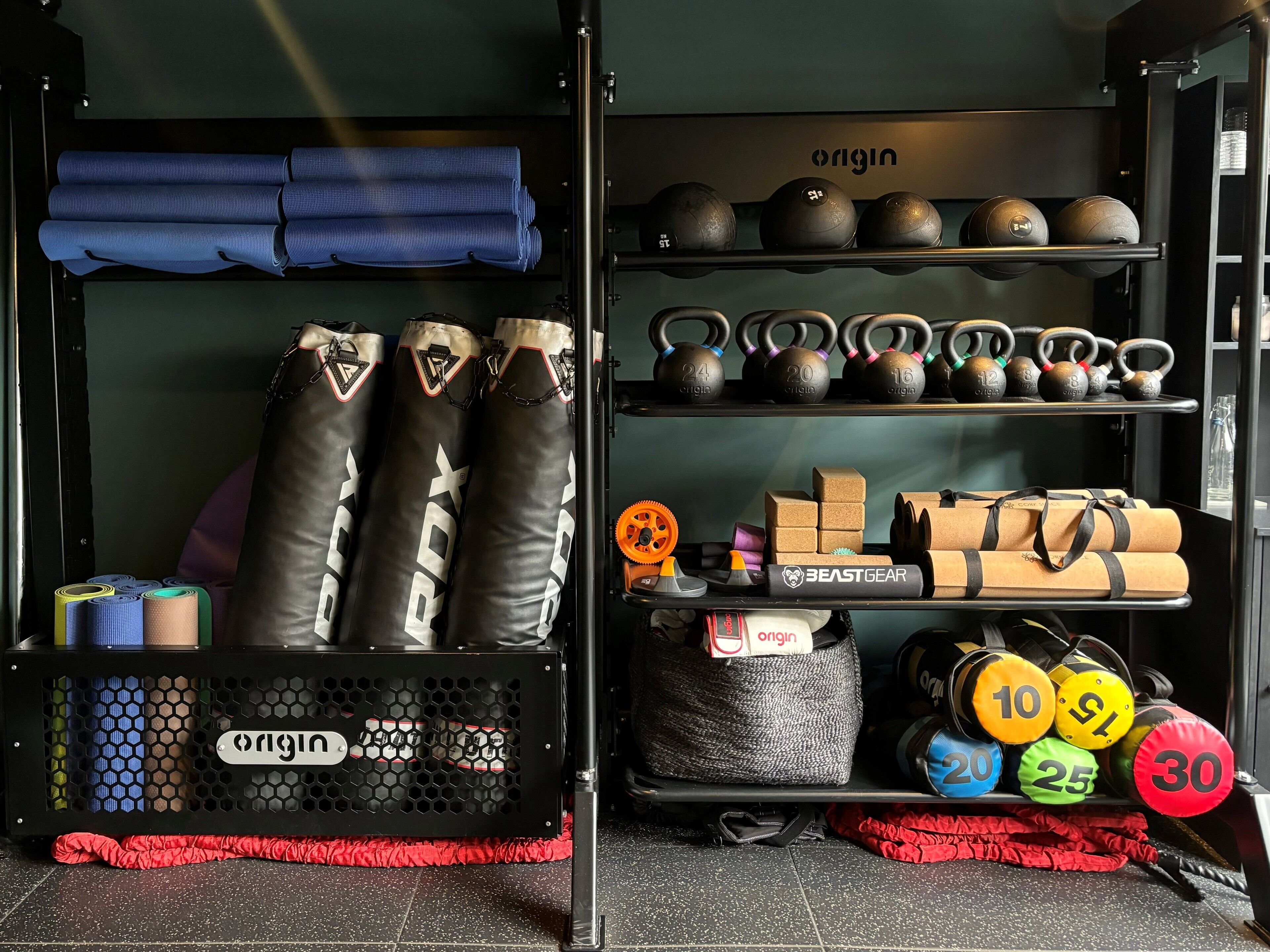 Un gimnasio con varios equipos de ejercicio, incluyendo pesas rusas, bandas de resistencia y colchonetas de yoga.