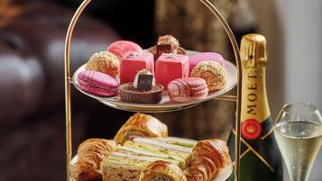 A tiered dessert stand with pastries and a bottle of champagne on a table.