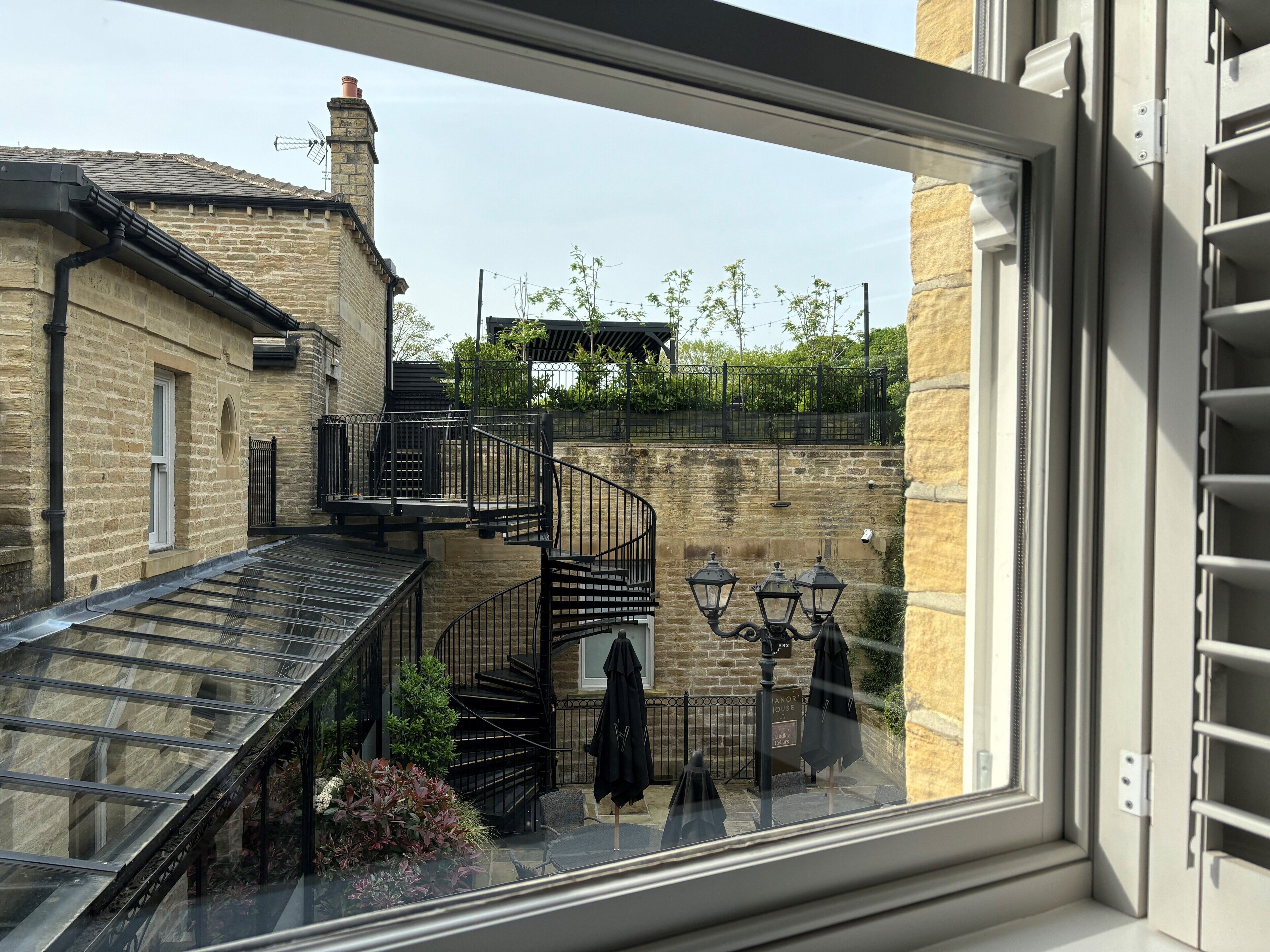A view of a courtyard with a stone building, a spiral staircase, and outdoor seating.