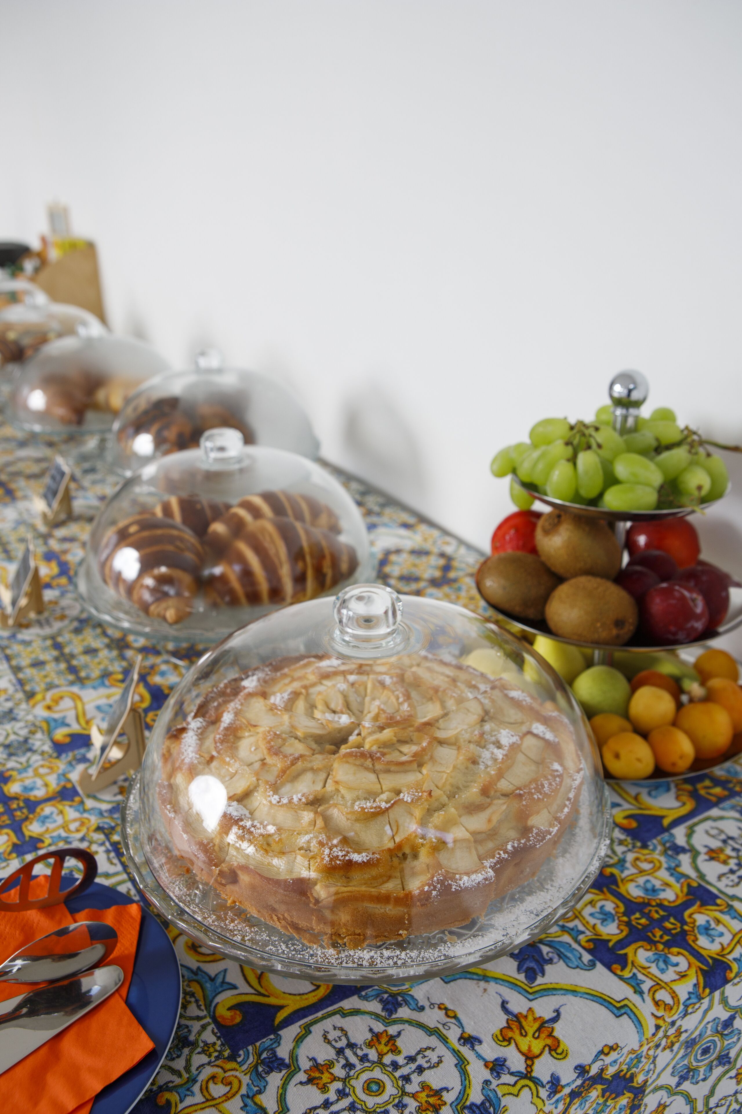 Una mesa con alimentos cubiertos y una exhibición de frutas.