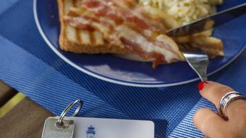 A plate with toast and scrambled eggs on a blue placemat, a keychain with a hotel key, and a name tag on a wooden table.