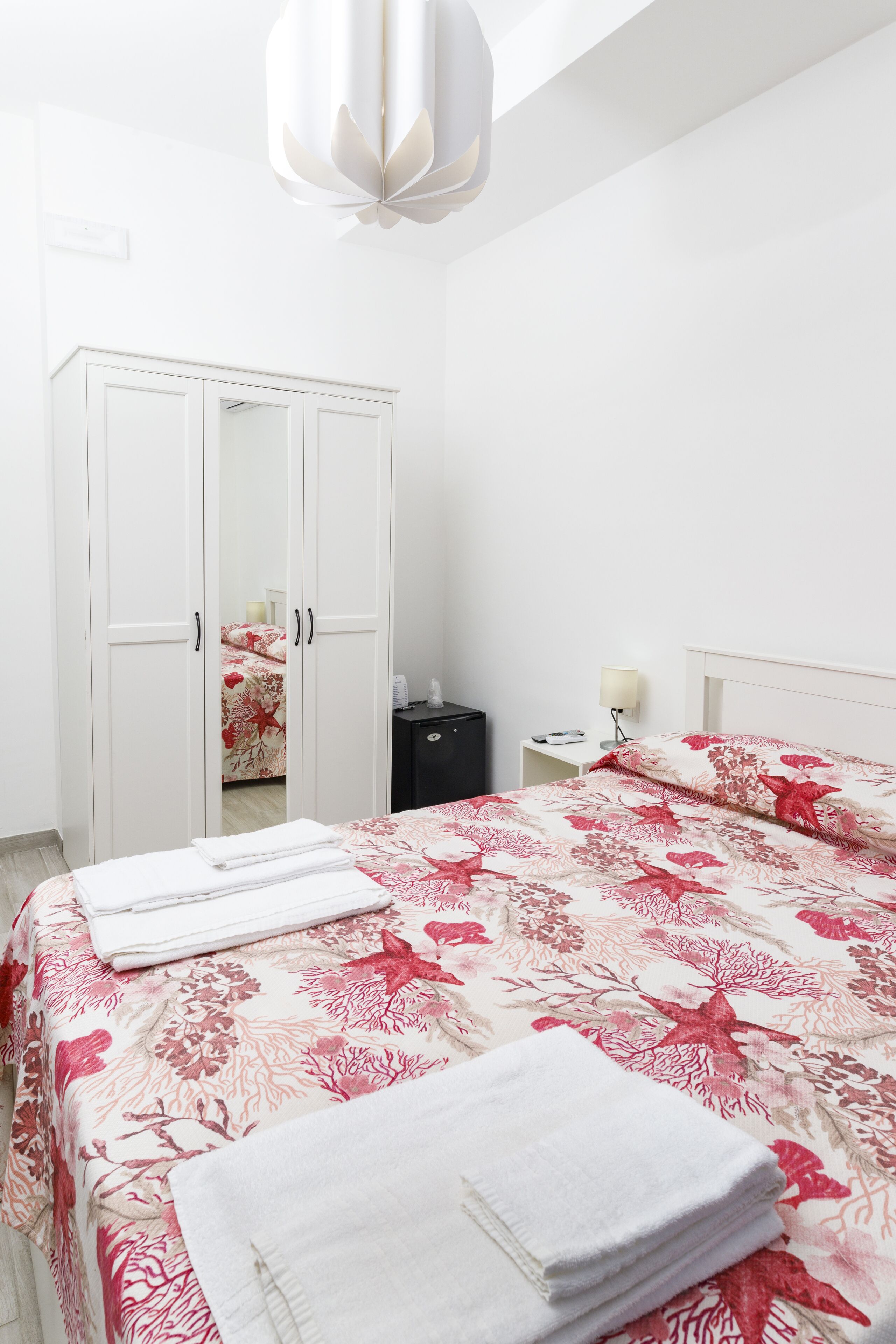 Quarto com cama, guarda-roupa, mesa de cabeceira e abajur.
