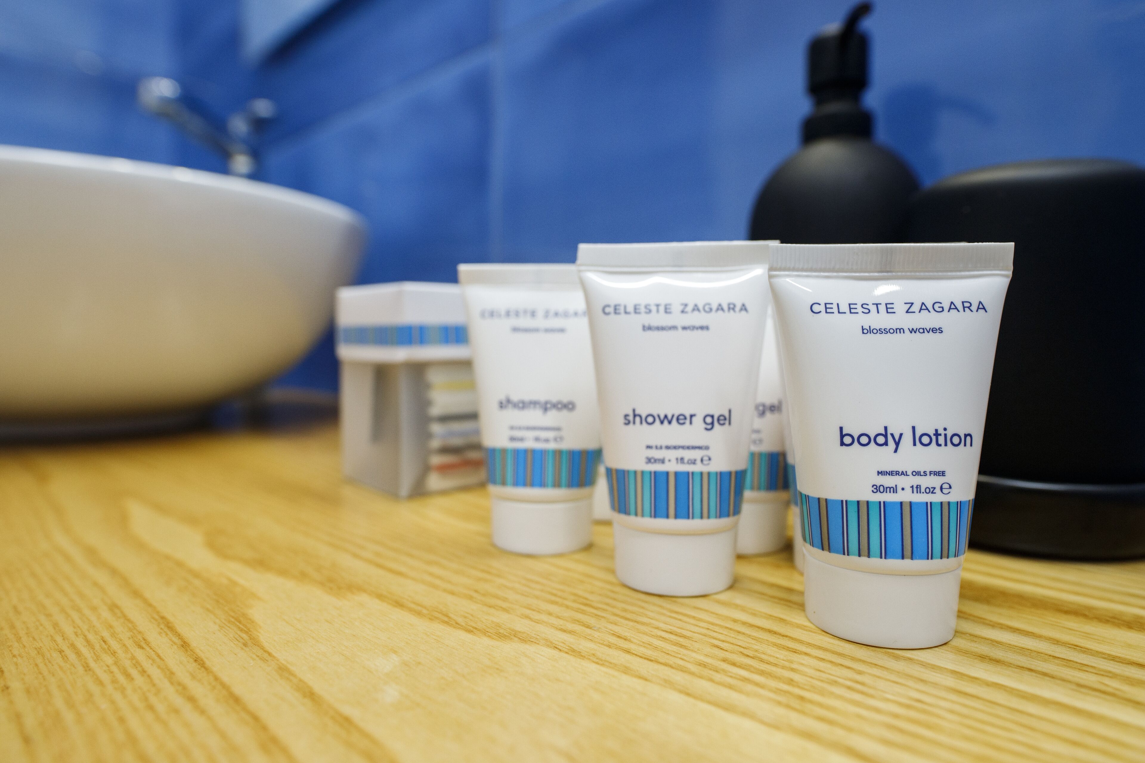 Una encimera de baño con artículos de aseo, incluyendo una loción corporal, gel de ducha y champú.