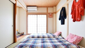 Un dormitorio de estilo japonés tradicional con suelo de tatami, un ventanal grande y una cama futón.