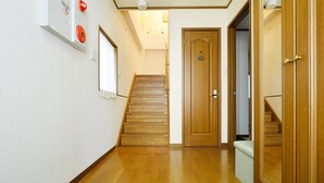 Un pasillo con piso de madera, una escalera y una puerta con un pequeño ventanal.