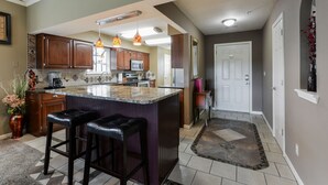 Una cocina amplia con una isla grande, armarios de madera e iluminación colgante.