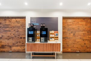 Una cafetería con dos máquinas de espresso, una pared de madera y un letrero que dice 'MUST HAVE COFFEE'.