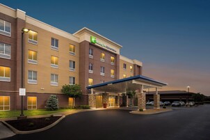 Edificio de Holiday Inn Express & Suites con entrada cubierta, zona de estacionamiento y fachada de ladrillo.