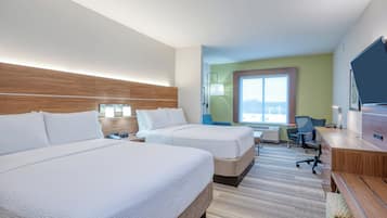 A hotel room with two beds, a desk, a chair, a television, and a window with a view.