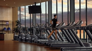 A gym with multiple treadmills, a large window with a view of the sky, and a television screen. - InterContinental Tianjin Yujiapu Hotel & Residences by IHG (Tianjin)