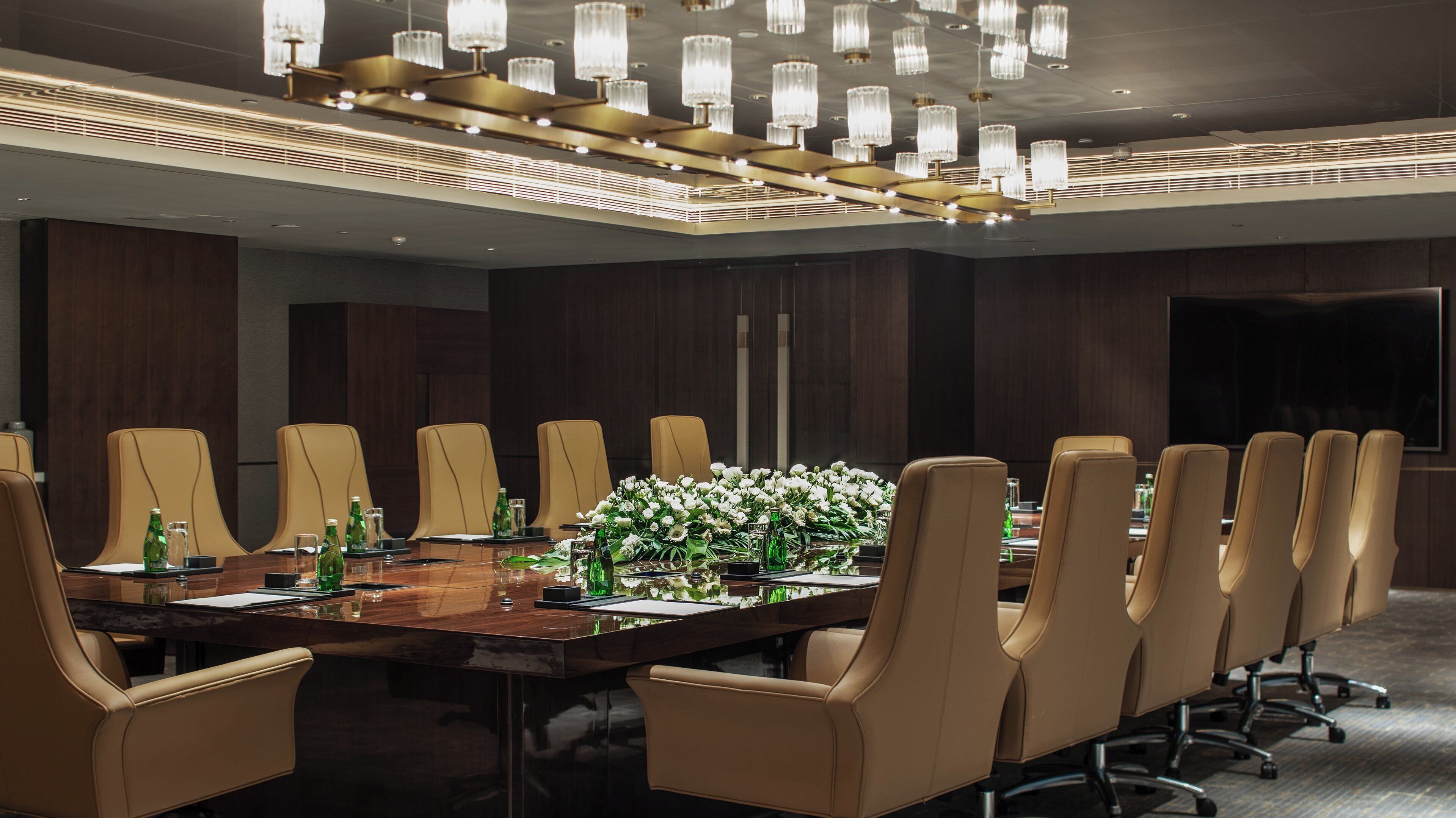A conference room with a long table, multiple chairs, and a chandelier.