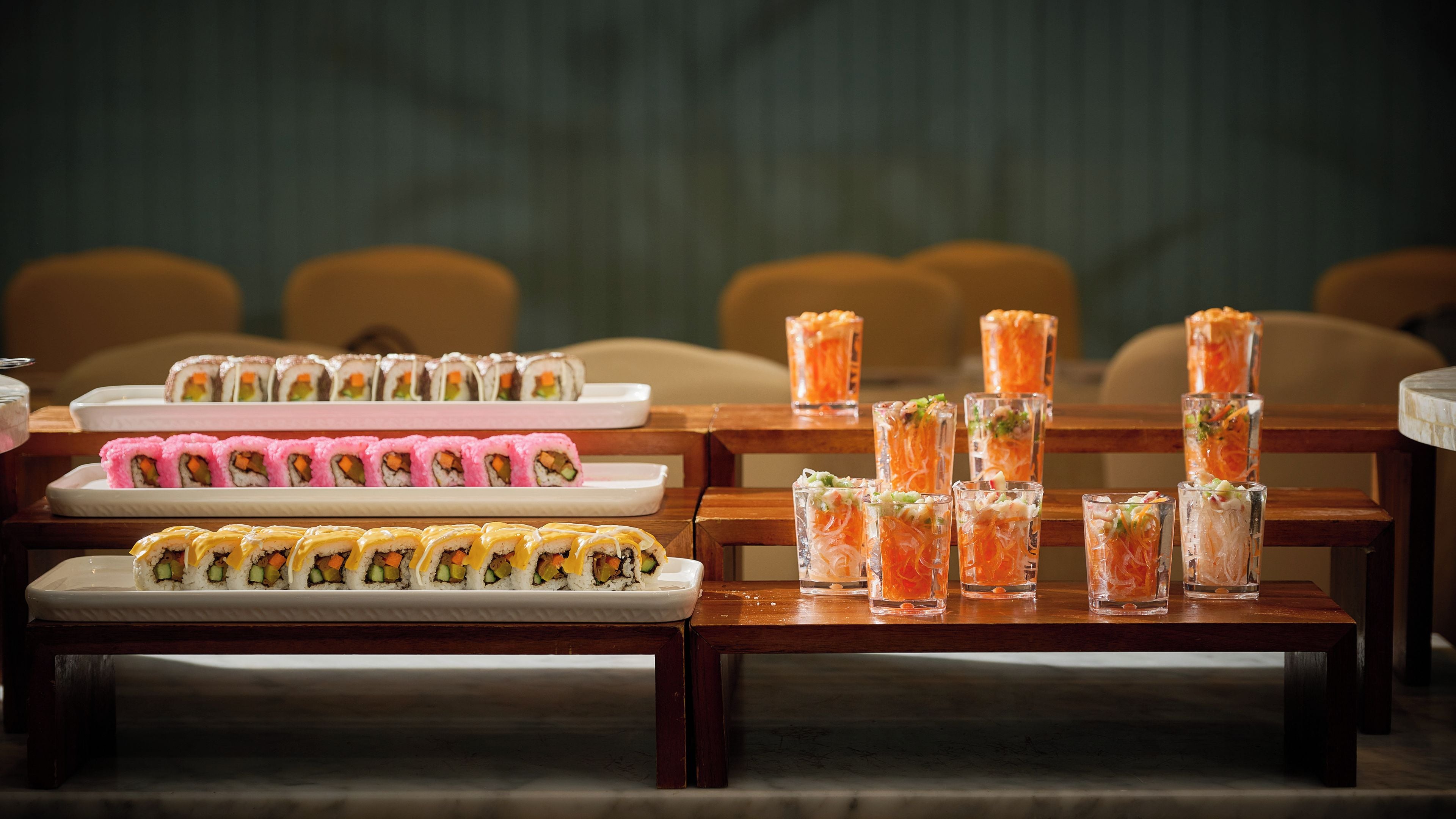 Un comedor con varias mesas dispuestas con sushi y bebidas.