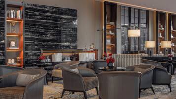 A modern hotel lobby with leather seating, a marble wall, and a large window.