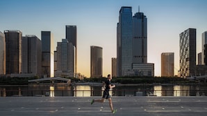 A runner on a waterfront path with a city skyline in the background. - InterContinental Tianjin Yujiapu Hotel & Residences by IHG (Tianjin)