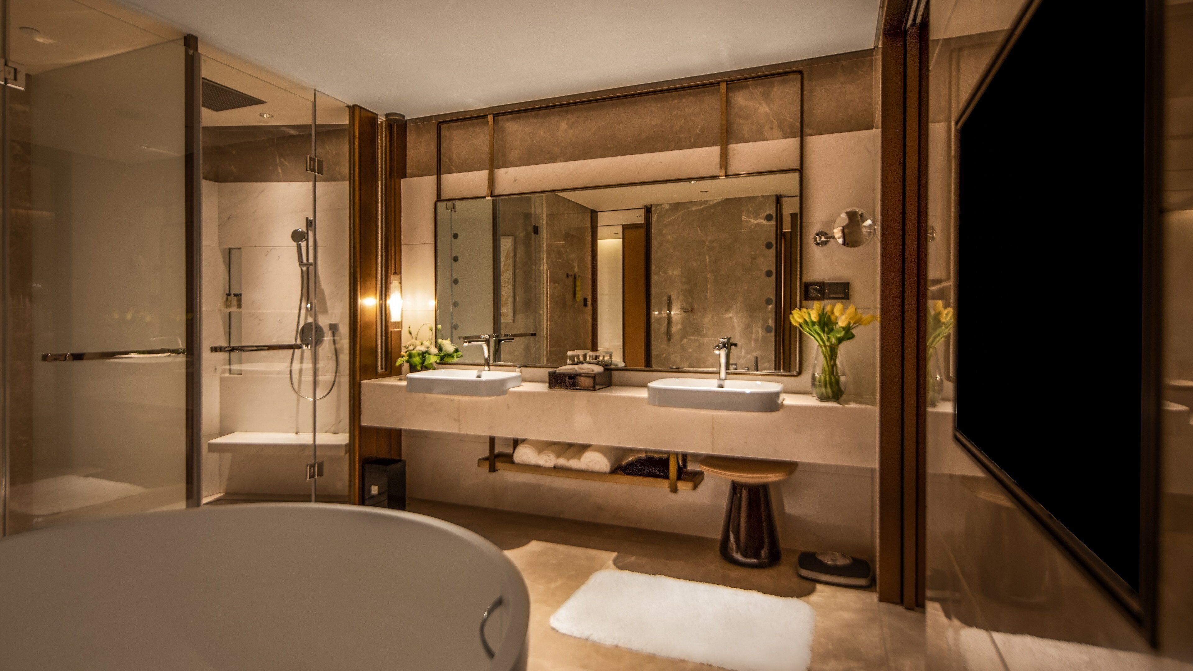 Un baño moderno con un espejo grande, dos lavamanos, una bañera y una ducha.