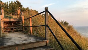Un escalier en bois menant à une plage, avec une rampe en métal.