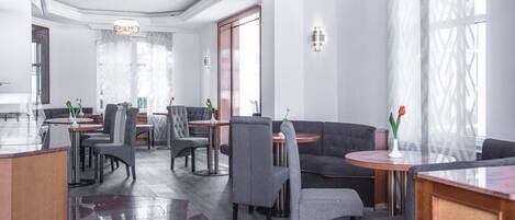 A modern hotel lobby with a bar area, seating arrangements, and large windows providing natural light.