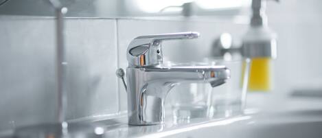 A modern bathroom sink with a chrome faucet and a soap dispenser.