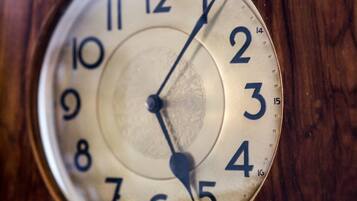 Primer plano de la esfera de un reloj con números y manecillas, montado sobre una superficie de madera.