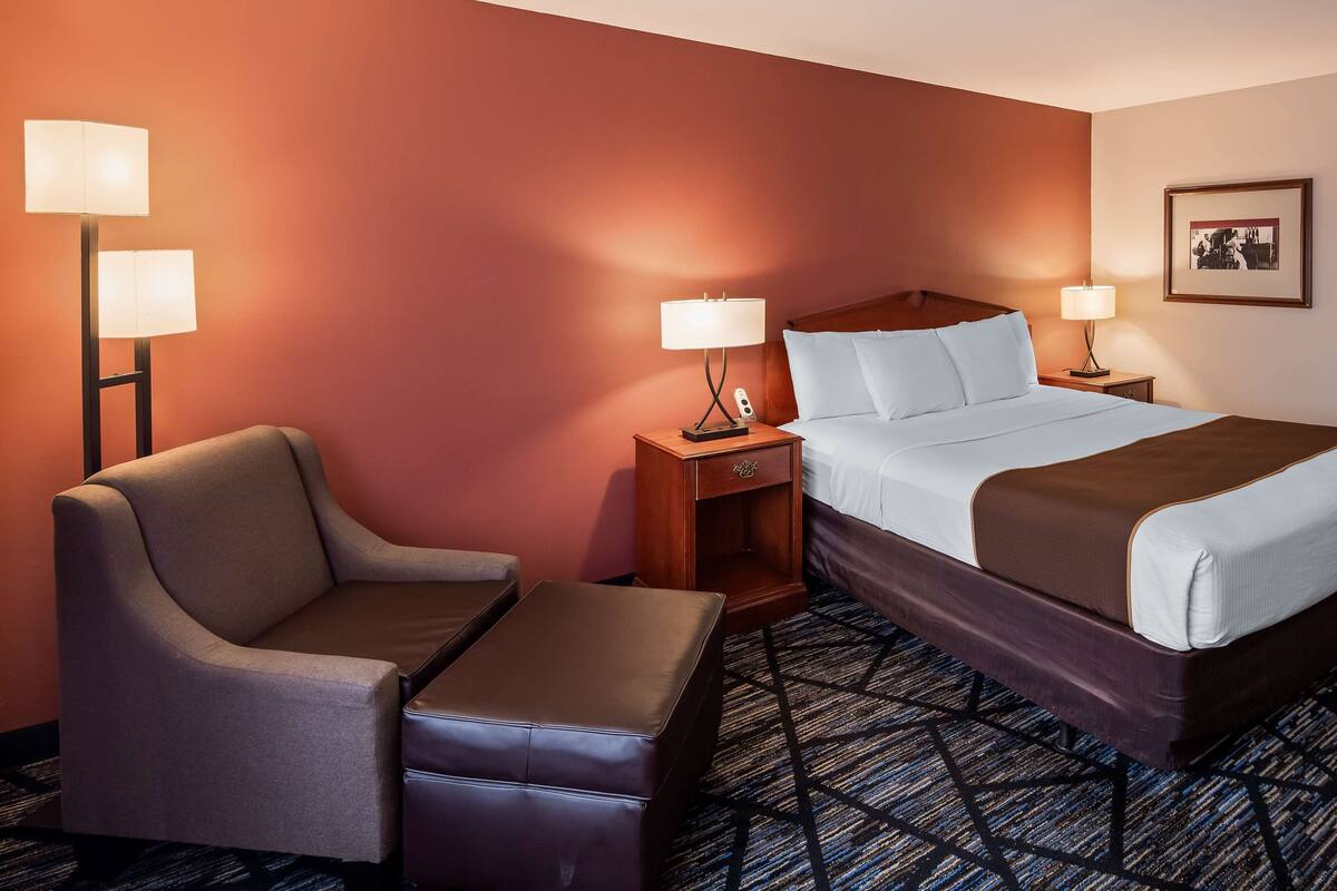 A hotel room with a bed, two bedside tables with lamps, a chair, and a small table.