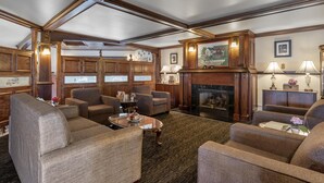 Un salon spacieux, doté de sièges confortables, d’une cheminée et de lambris en bois.
